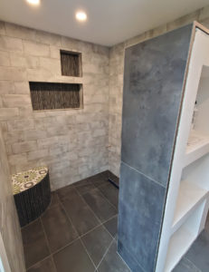 A walk in shower with tile and a built-in bench.