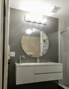 A bathroom remodel featuring a round mirror.