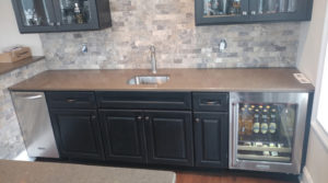 A sink area with a built-in mini fridge and backsplash.