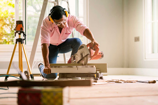 a contractor wearing protective earmuffs works in a bright unfinished home
