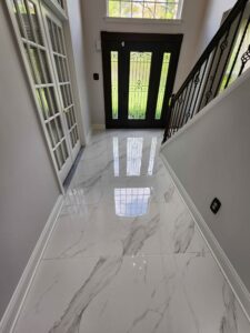 A remodeled front hall with a reflective marble flooring, a stairway, and a fancy front door with blurry glass.