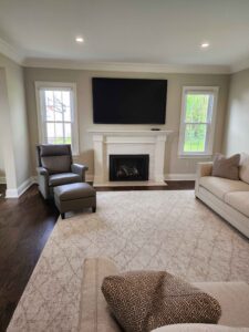 A remodeled living room with a beautiful wood flooring, along with a fireplace, wall-mounted tv, and nice furniture.